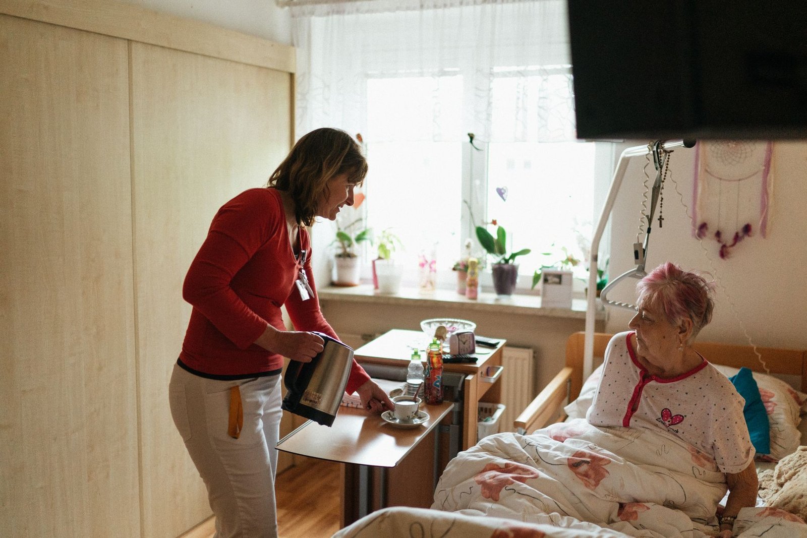 Caregiver serving tea to an older woman in a care setting